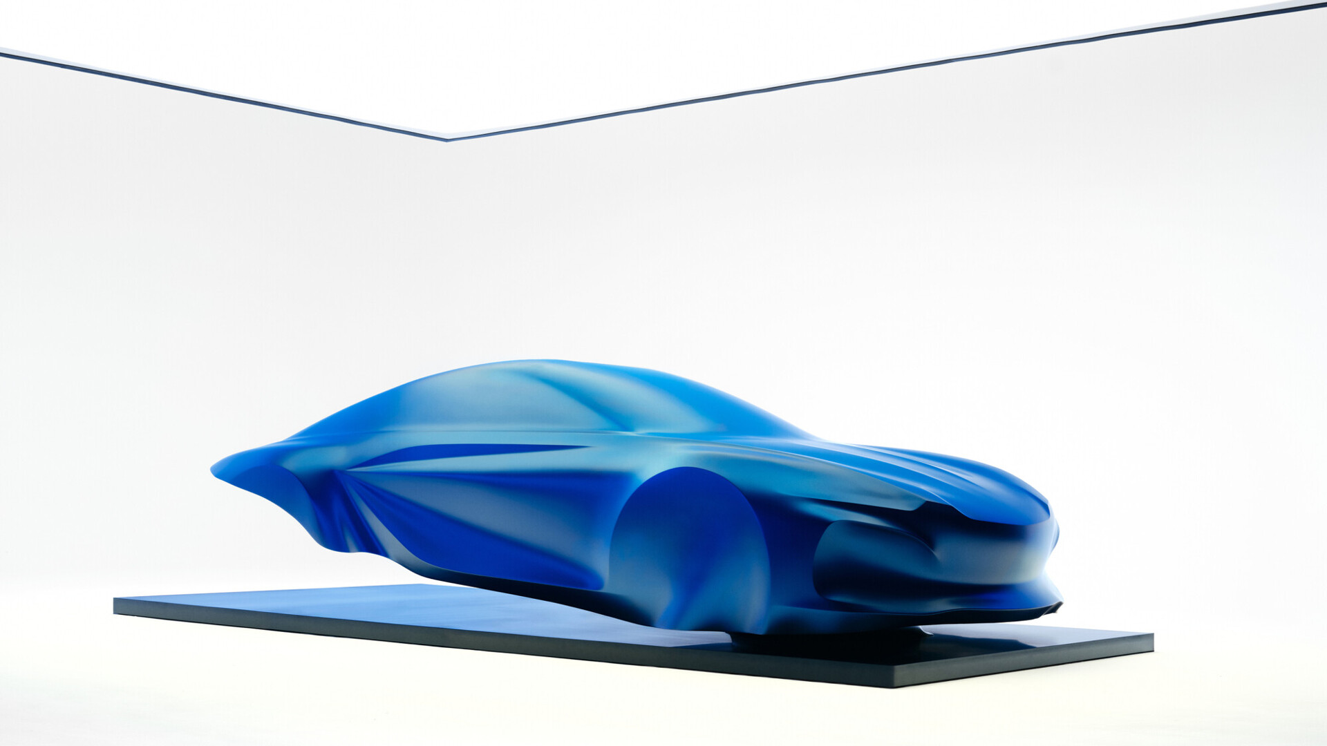 Blue draped sculpture previewing the third-generation Alpine A110 on a floating black plinth