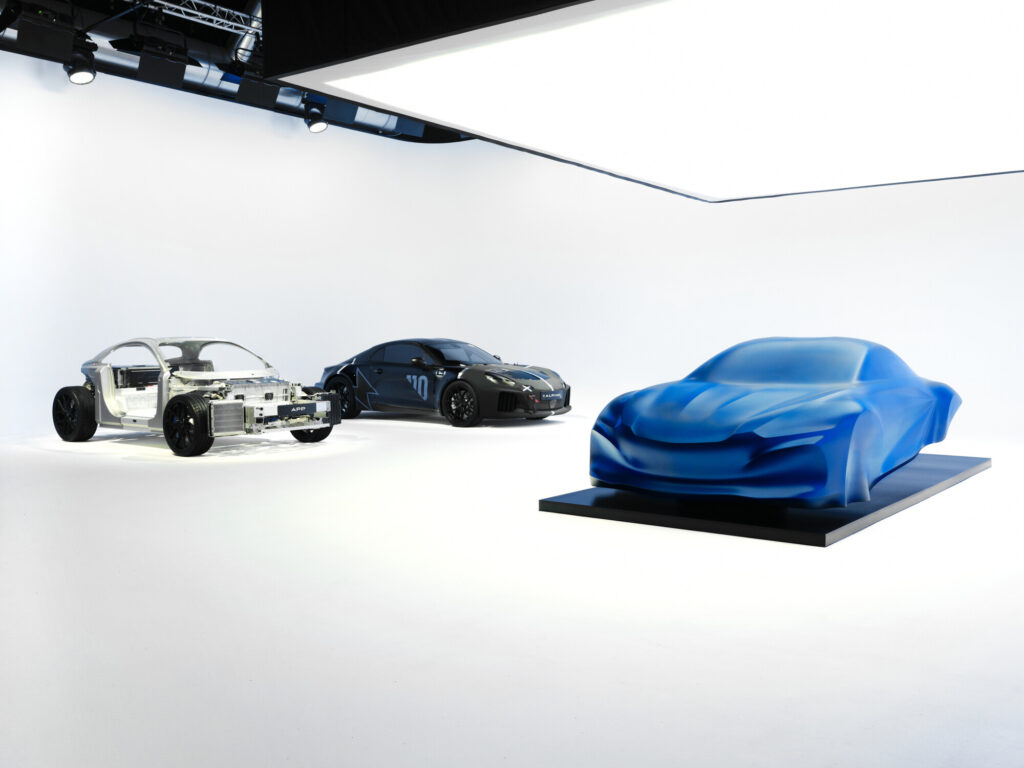 Bare Alpine Performance Platform chassis, camouflaged A110 FUTURE development mule and blue draped A110 sculpture in a white studio