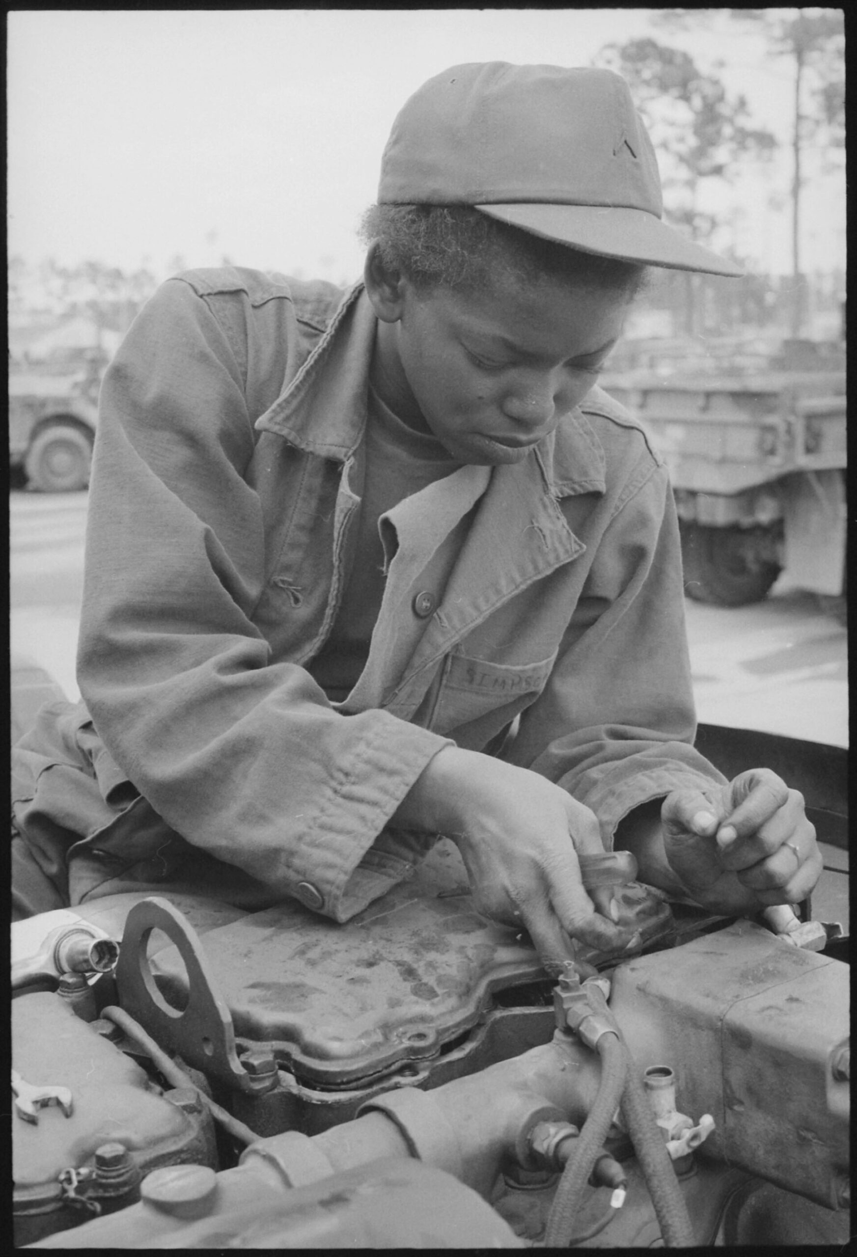 A female Army auto mechanic working on the engine of a 5-ton truck