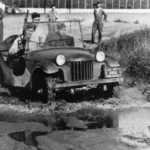 Bantam pilot jeep prototype carrying three soldiers through mud during Army testing at Camp Holabird in 1940