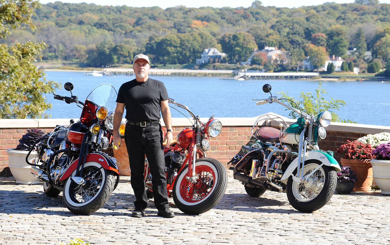 Billy Joel standing with three Harley-Davidson motorcycles
