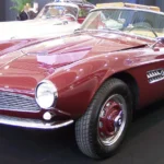 A red BMW 507 roadster on display at a classic car show, front three-quarter view