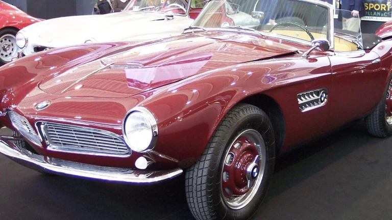 A red BMW 507 roadster on display at a classic car show, front three-quarter view