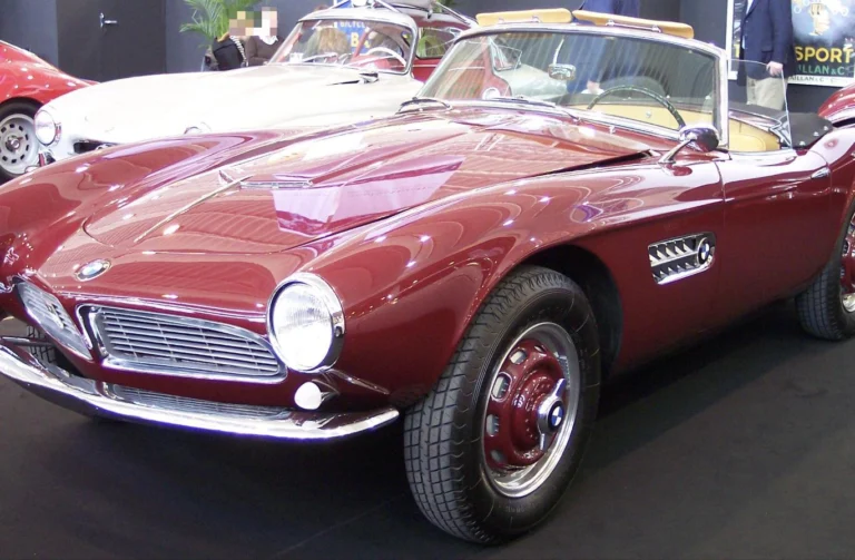 A red BMW 507 roadster on display at a classic car show, front three-quarter view