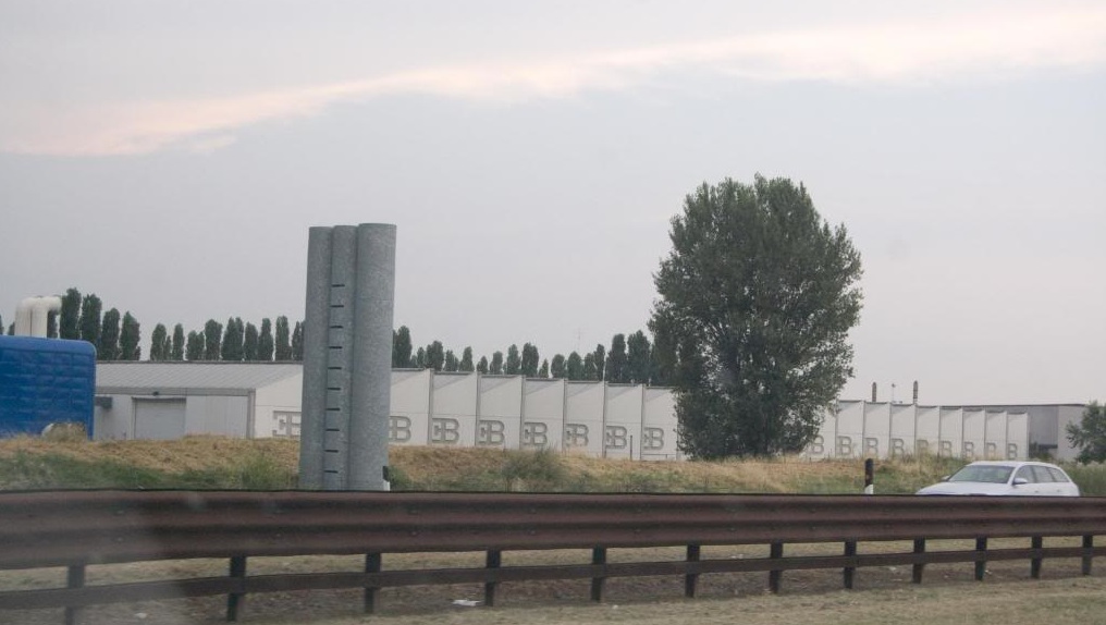 Exterior view of the Bugatti Automobili factory at Campogalliano with its assembly hall and engine department behind a roadside guardrail