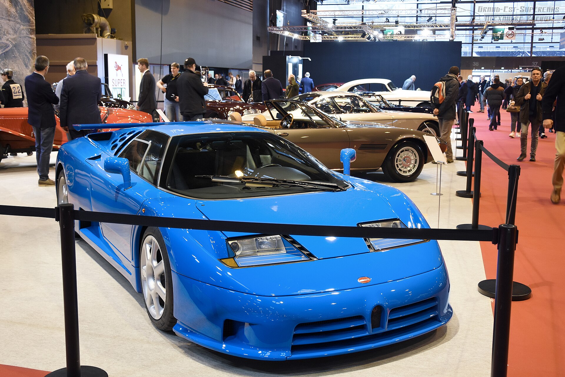 Blue Bugatti EB110 Super Sport displayed front three-quarter, showing its wedge nose, horseshoe grille and scissor-door greenhouse