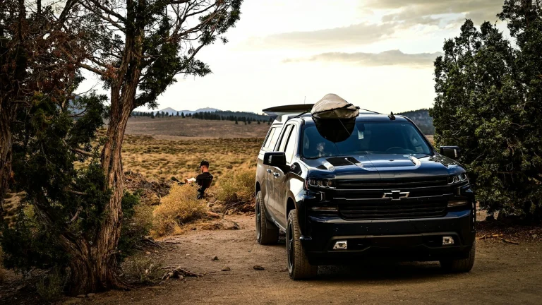 Black Chevrolet Silverado 1500 pickup parked on a dirt trail