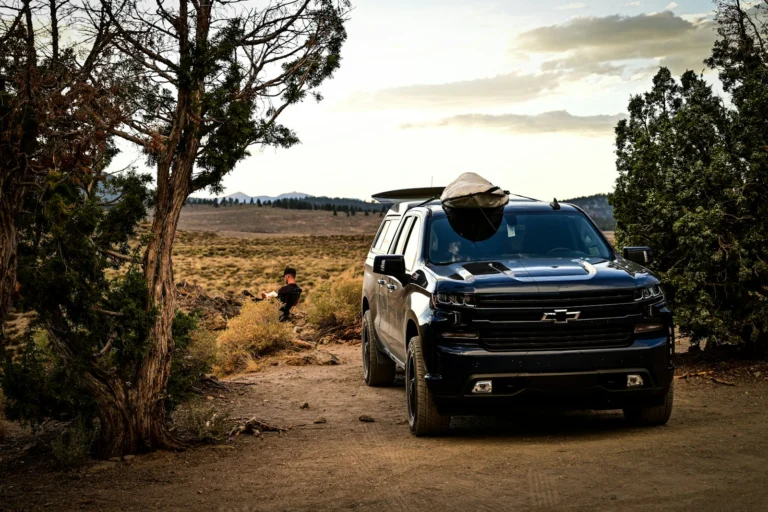 Black Chevrolet Silverado 1500 pickup parked on a dirt trail