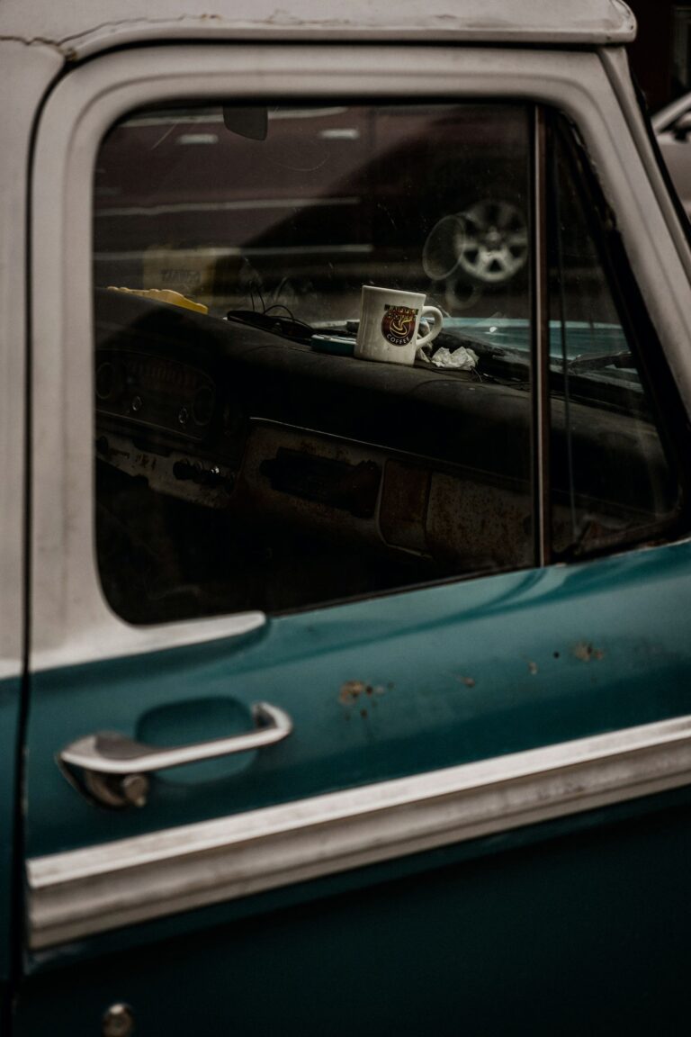 A coffee mug sitting on the dashboard of a weathered vintage pickup truck