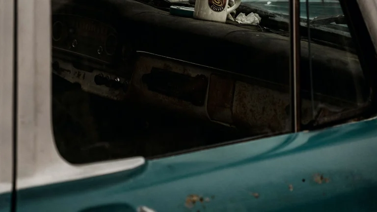A coffee mug sitting on the dashboard of a weathered vintage pickup truck