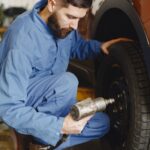 Technician using a cordless impact wrench on a car wheel during tire service