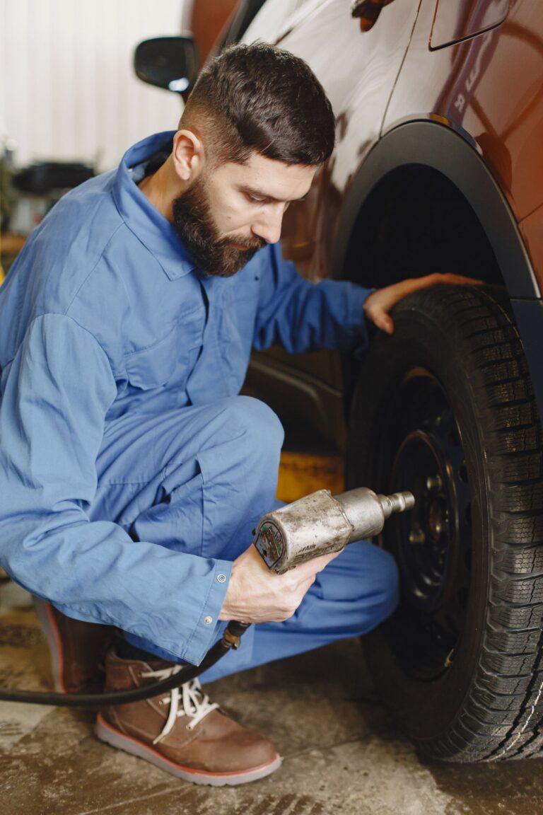 Technician using a cordless impact wrench on a car wheel during tire service