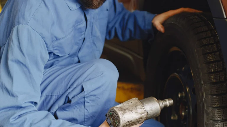 Technician using a cordless impact wrench on a car wheel during tire service