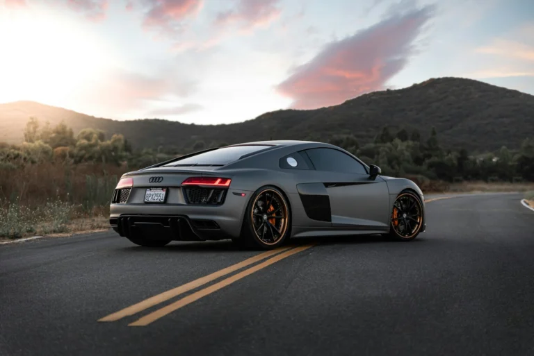 A matte grey Audi R8 sports car on a winding road at golden hour