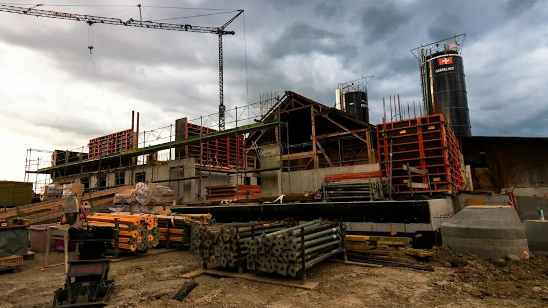 Construction site with a crane and formwork under a stormy sky