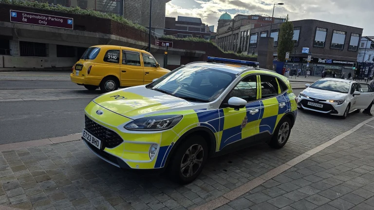 A yellow and blue Battenburg-liveried police car parked near Derby bus station