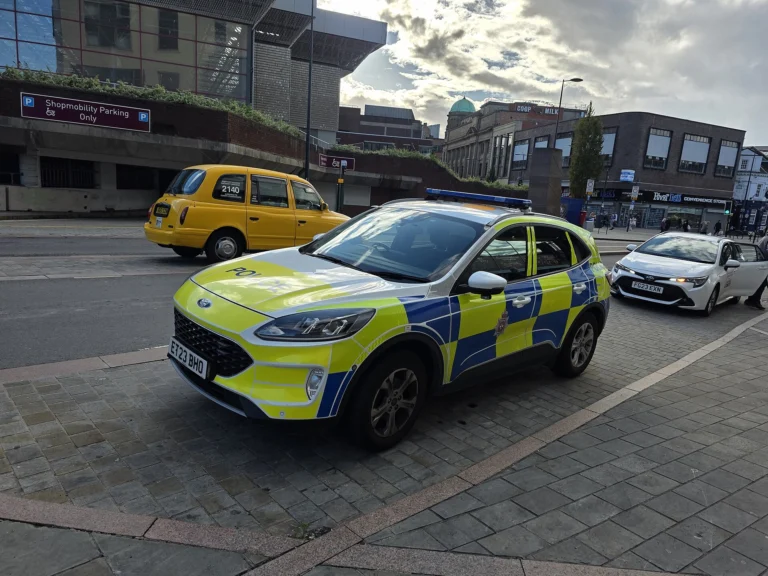 A yellow and blue Battenburg-liveried police car parked near Derby bus station