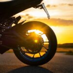 Motorcycle wheel at sunset with sun flare
