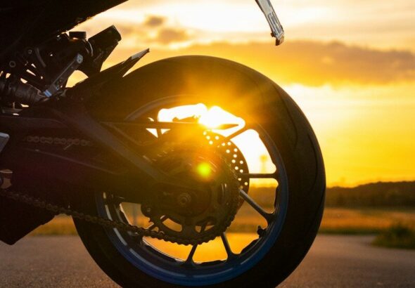 Motorcycle wheel at sunset with sun flare