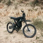 Black electric dirt bike without pedals parked on a rocky trail