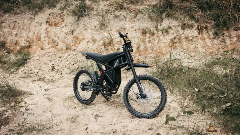 Black electric dirt bike without pedals parked on a rocky trail