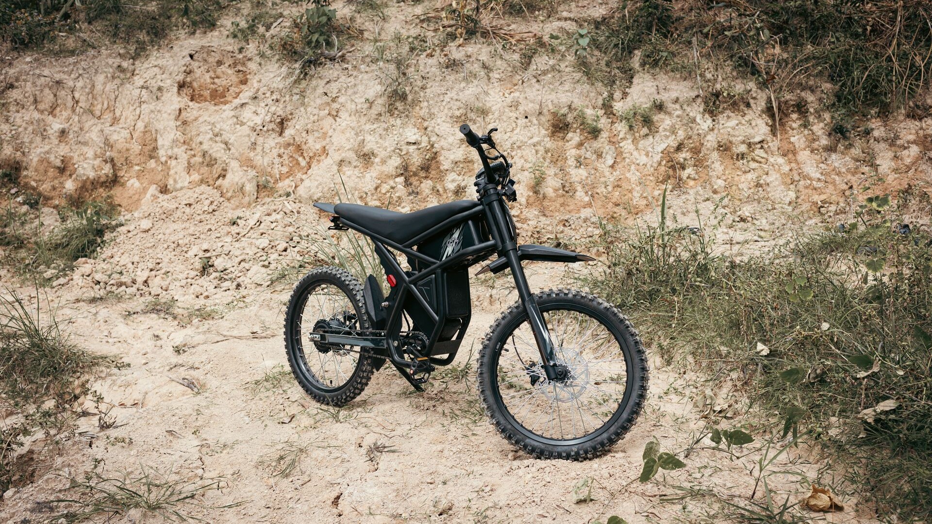 Black electric dirt bike without pedals parked on a rocky trail