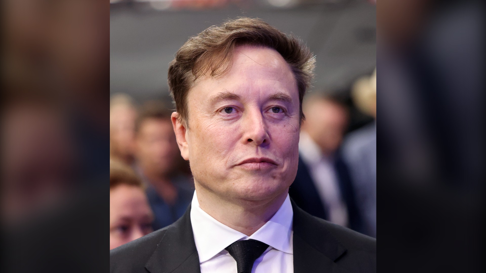 Elon Musk in a dark suit and tie