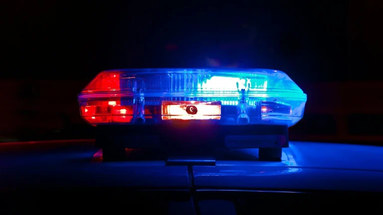 A police light bar flashing red and blue against a dark night background
