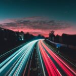 Long-exposure highway light trails at night, evoking red and blue emergency lighting