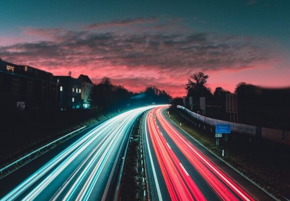 Long-exposure highway light trails at night, evoking red and blue emergency lighting