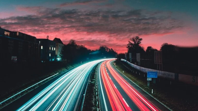 Long-exposure highway light trails at night, evoking red and blue emergency lighting