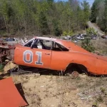 Rusting orange 1969 Dodge Charger General Lee replica with 01 on the door in a Georgia junkyard