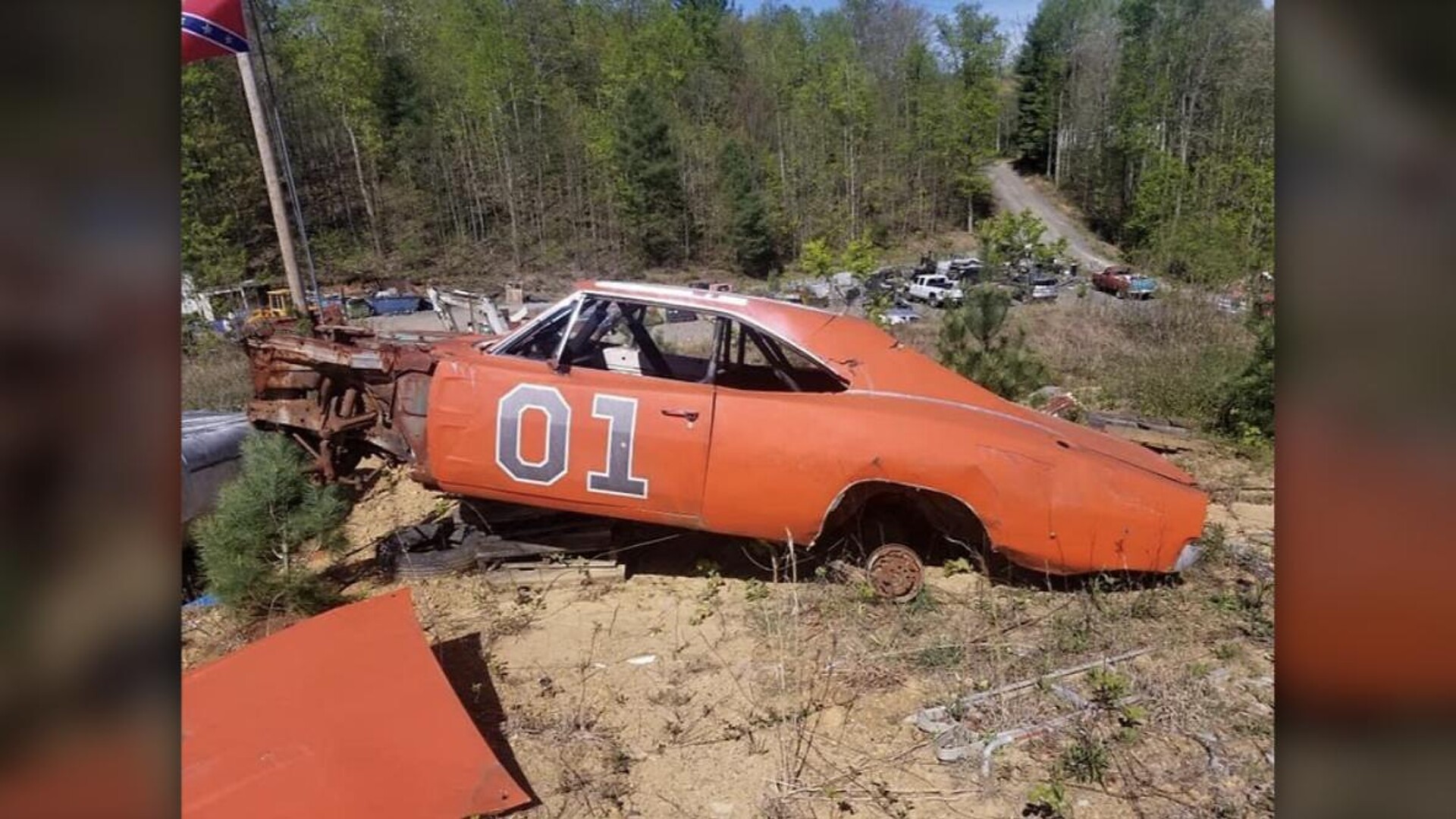 Rusting orange 1969 Dodge Charger General Lee replica with 01 on the door in a Georgia junkyard
