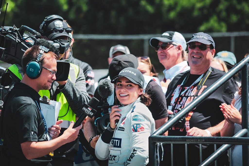 Jamie Chadwick smiling during a TV interview in the paddock