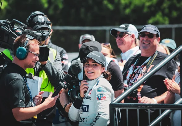 Jamie Chadwick smiling during a TV interview in the paddock