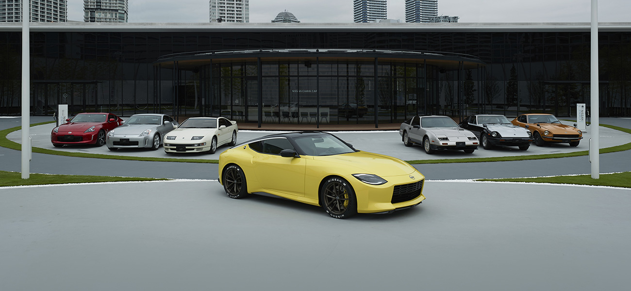 A yellow Nissan Z Proto parked in front of earlier generations of the Nissan Z