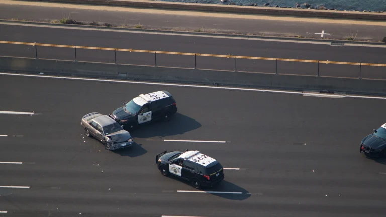 A patrol car uses a PIT maneuver to spin a fleeing vehicle on a highway