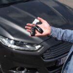 Hand holding car key fob outside a rental vehicle