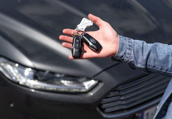 Hand holding car key fob outside a rental vehicle