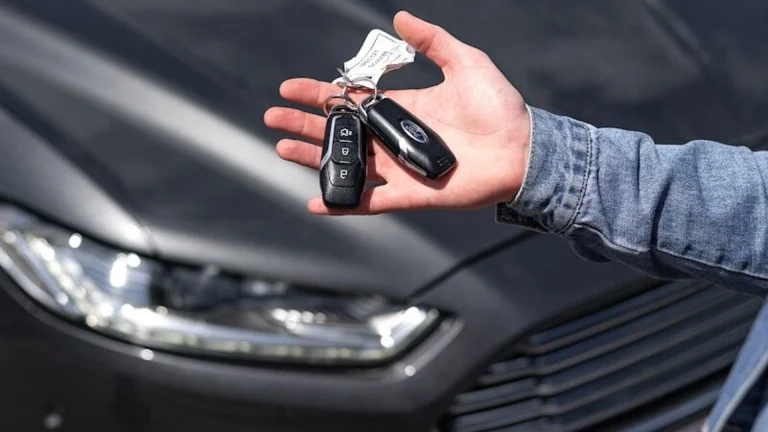 Hand holding car key fob outside a rental vehicle