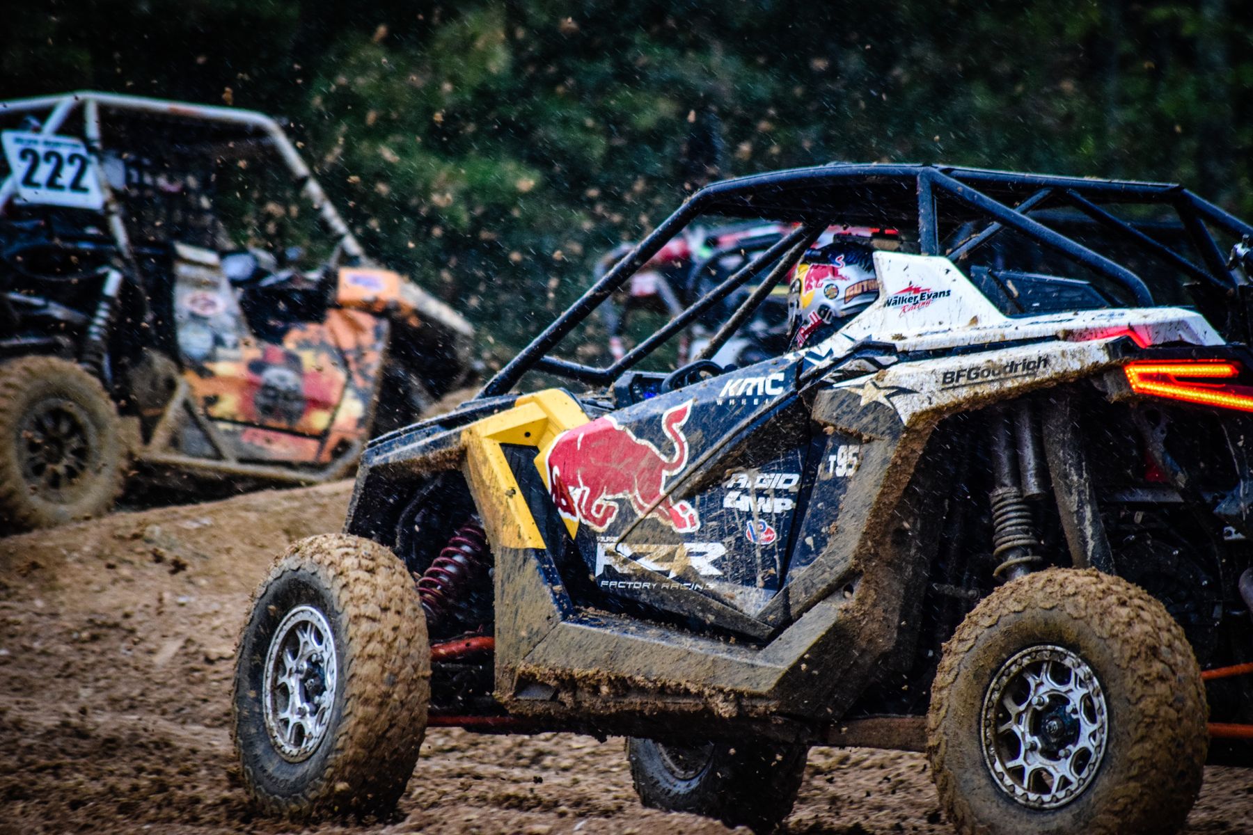 Polaris RZR Factory Racing side-by-side charging through a rutted off-road racecourse ahead of a rival UTV