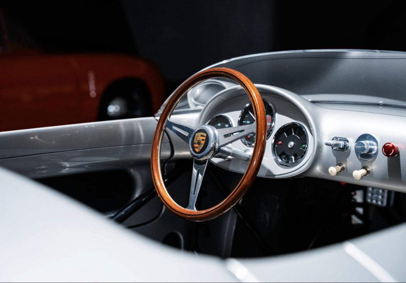 Close-up of the Porsche 550 J cockpit with wood-rimmed three-spoke steering wheel and analog gauges