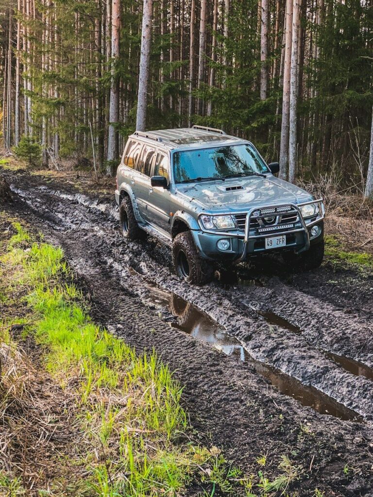 Nissan Patrol 4x4 wading through a muddy off-road trail