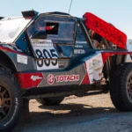 Red recovery boards mounted on the side of a desert rally car in Jordan