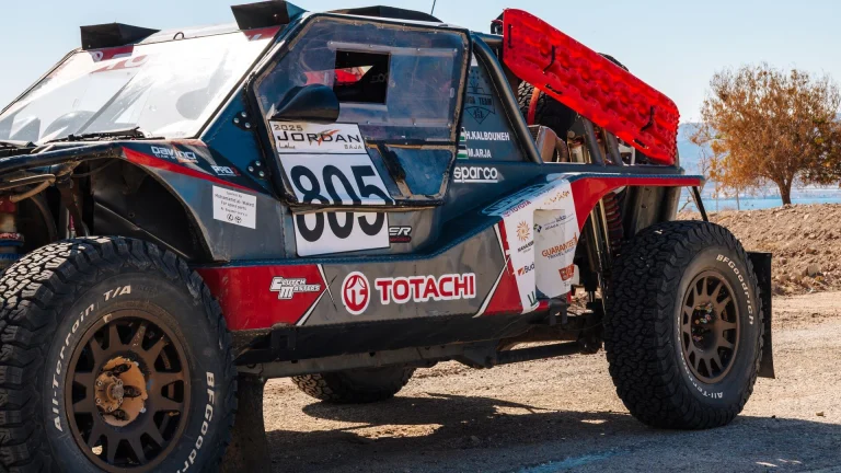 Red recovery boards mounted on the side of a desert rally car in Jordan