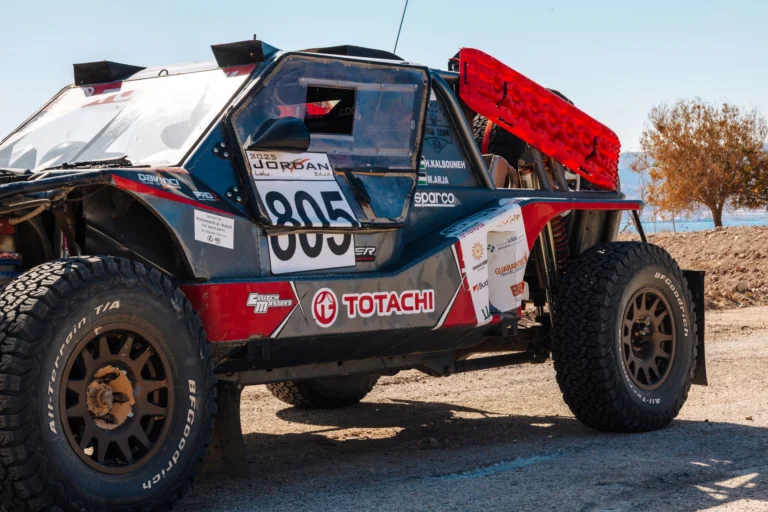 Red recovery boards mounted on the side of a desert rally car in Jordan