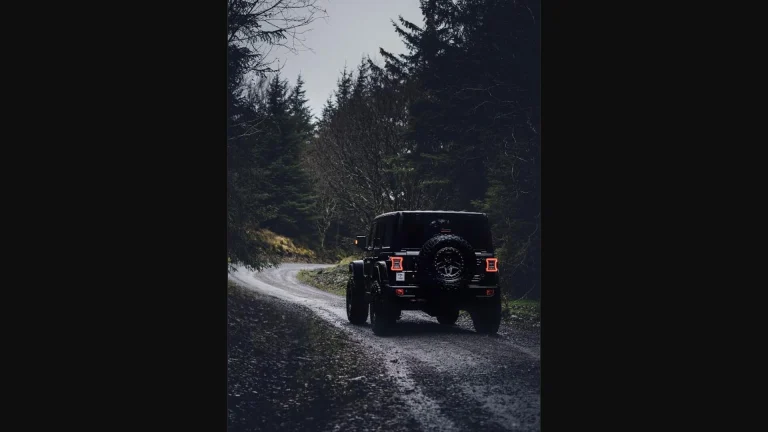 Black off-road SUV driving down a forest gravel trail, representing the rugged Scout Traveler Trail-Ready concept