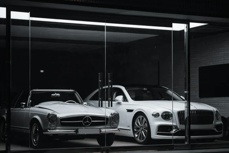 A vintage Mercedes-Benz and a modern Bentley parked behind a glass storefront