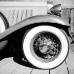 Black-and-white view of a 1920s open sports car showing its wire-spoked wheel and minimal cycle fender