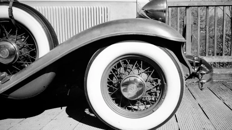 Black-and-white view of a 1920s open sports car showing its wire-spoked wheel and minimal cycle fender